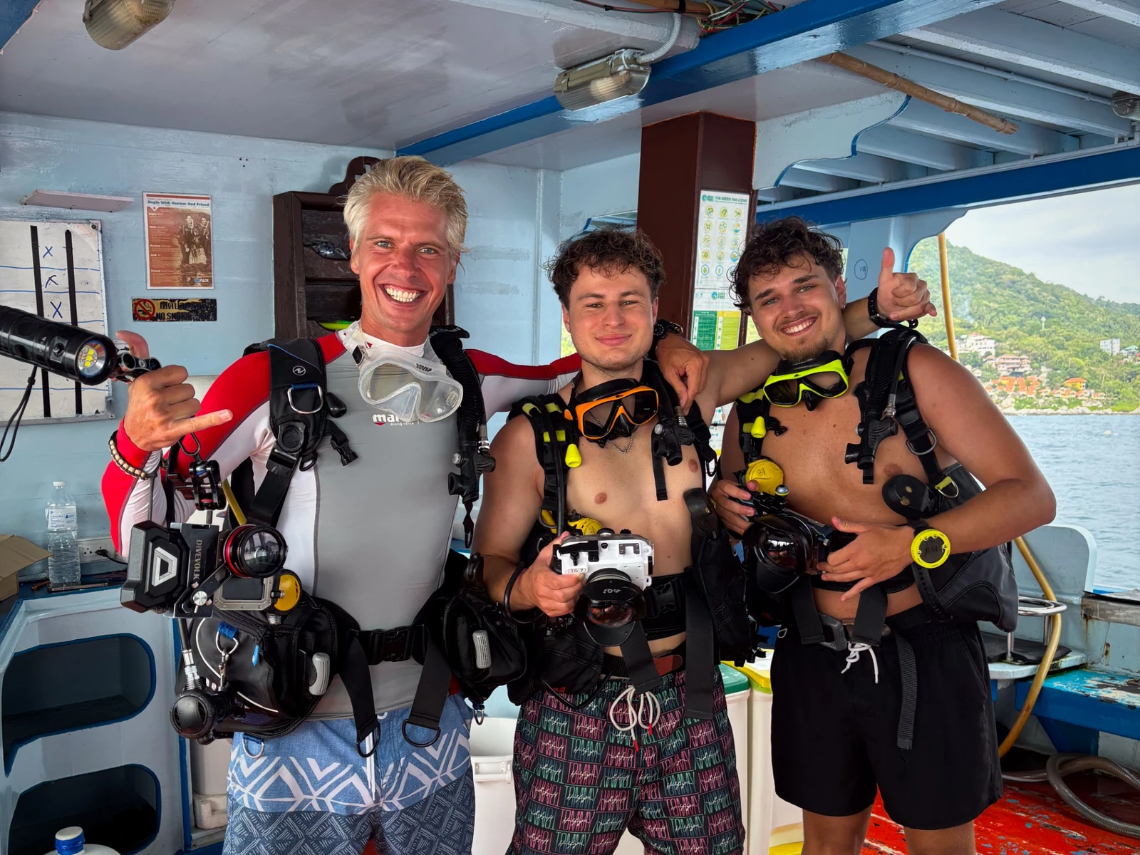 ason standing on the dive boat with his underwater photography course students, all geared up with cameras and scuba equipment, smiling before the dive